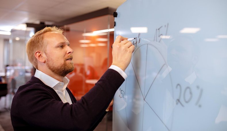 Mann schreibt auf Whiteboard.